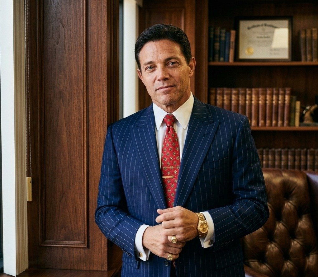 Confident Jordan Belfort posing in a luxurious mahogany wood office.