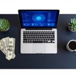 Laptop showing AI dashboard on desk with dollar bills — entry level AI jobs for students